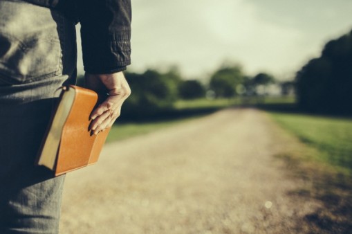 man-holding-a-Bible-at-his-side-looking-down-a-long-dirt-road-Travis-Hallmark-760x506.2451246_std
